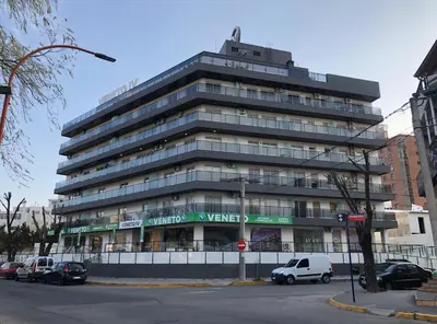 a tall building with cars parked in front of it at Edificio Veneto III - Departamento de un dormitorio a pocas cuadras del centro in Villa Carlos Paz