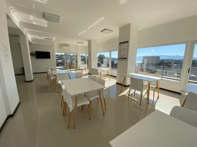 a dining room with white tables and chairs and windows at Edificio Veneto III - Departamento de un dormitorio a pocas cuadras del centro in Villa Carlos Paz