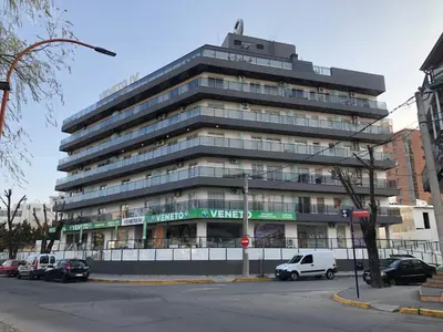a large building with cars parked in front of it at Edificio Veneto IV - Departamento de un dormitorio a una cuadra de la peatonal in Villa Carlos Paz