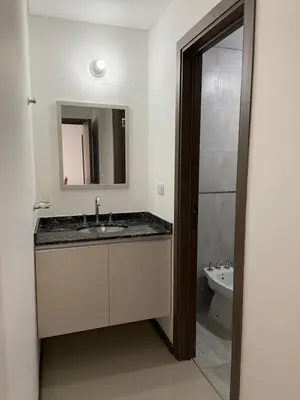 a bathroom with a sink and a mirror and a toilet at Edificio Veneto IV - Departamento de un dormitorio a una cuadra de la peatonal in Villa Carlos Paz