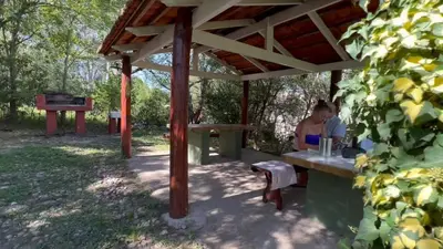 a woman sitting at a picnic table under a pavilion at La Casa de Pipa in Mina Clavero