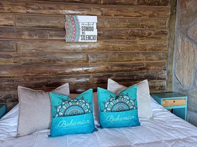 a bed with blue pillows and a wooden wall at Sommerwind Cabañas in La Estancia