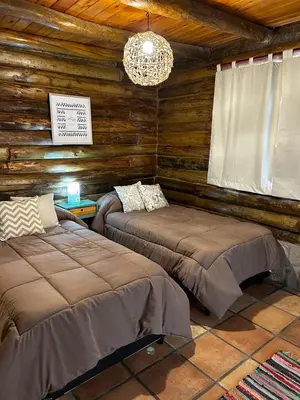 a bedroom with two beds in a log cabin at Sommerwind Cabañas in La Estancia