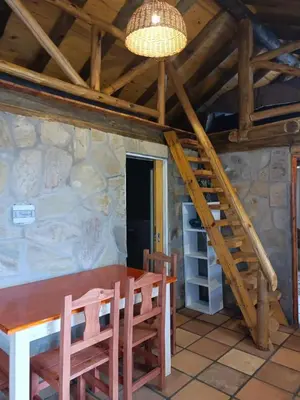 a dining room with a wooden table and a staircase at Sommerwind Cabañas in La Estancia