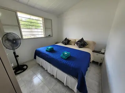 a bedroom with a bed with blue sheets and a fan at Casa en Montaña 2 habitaciones con cochera, apto mascotas in Villa Carlos Paz