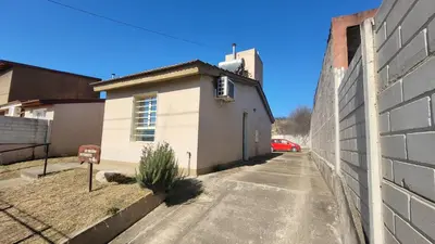 a small white building next to a wall at Casa en Montaña 2 habitaciones con cochera, apto mascotas in Villa Carlos Paz