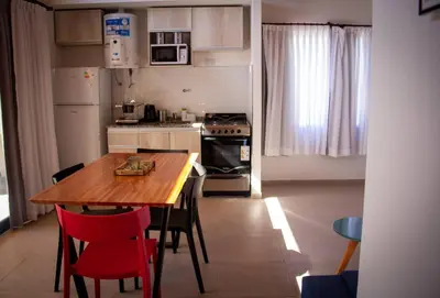 a kitchen with a wooden table and red chairs at TERRA CIMINTO in Villa Rumipal