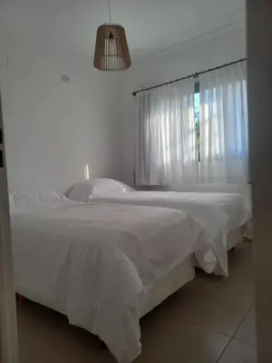 a bedroom with two beds with white sheets and a window at TERRA CIMINTO in Villa Rumipal