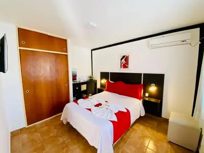 a bedroom with a large bed with red pillows at Hosteria Aguaribay in Mina Clavero