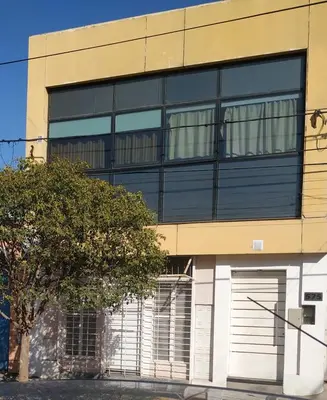 a building with two garage doors and a tree at Habitación para 2 personas con baño privado in Cordoba