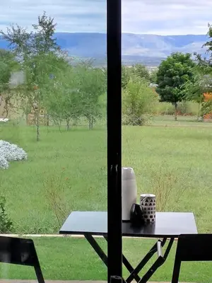 a table in front of a window with a view of a field at Hada del Champaqui - Posada de Montaña in Villa General Belgrano