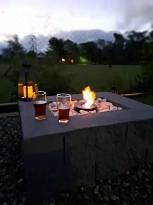 a fire pit with two glasses of beer and a fire at Hada del Champaqui - Posada de Montaña in Villa General Belgrano