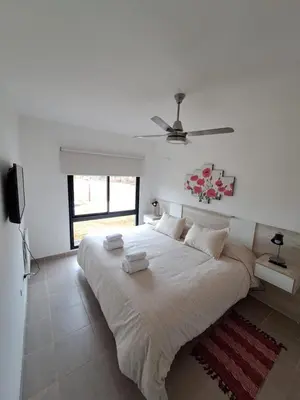 a white bedroom with a large bed with a ceiling fan at Hada del Champaqui - Posada de Montaña in Villa General Belgrano
