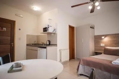 a room with a bed and a table and a kitchen at Altos del Champaqui in Villa Carlos Paz
