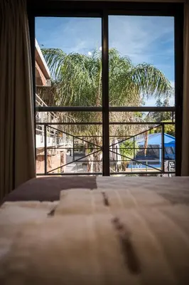 a bedroom with a view of a palm tree from a window at Altos del Champaqui in Villa Carlos Paz
