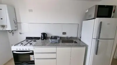 a kitchen with a stove and a sink and a refrigerator at Hermoso departamento temporario en zona centro a metros de la terminal e importantes hospitales in Cordoba