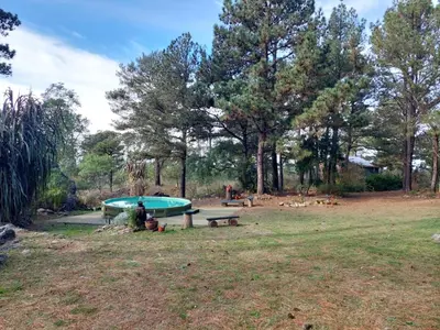 a person sitting next to a pool in a park at Luna Plateada - Terrafirme in Villa Yacanto