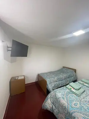 a room with two beds and a tv on the wall at Monoambiente El Sosiego in Alta Gracia