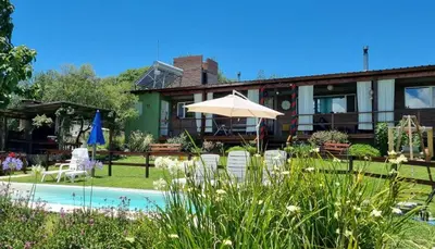 a house with a pool and chairs and an umbrella at Abrazados Suites del Valle in Villa Yacanto