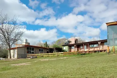 a building with a grass field in front of it at Abrazados Suites del Valle in Villa Yacanto