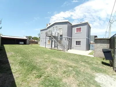 a gray house with a lawn in front of it at Departamentos Universidad in Río Cuarto