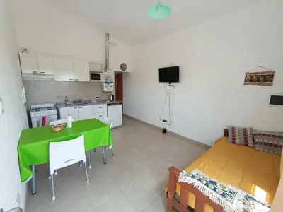 a living room with a green table and a kitchen at Departamentos Universidad in Río Cuarto