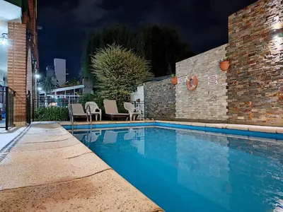 a swimming pool with chairs next to a building at Posada El Betel in Villa Carlos Paz