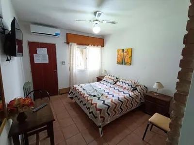 a bedroom with a bed and a table and a window at Posada El Betel in Villa Carlos Paz