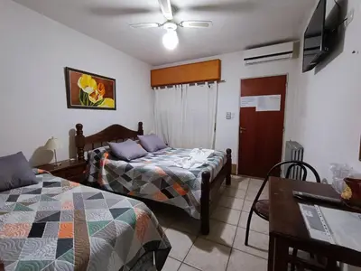 a bedroom with two beds and a table and a fan at Posada El Betel in Villa Carlos Paz