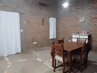a dining room with a table and chairs and a kitchen at Casa del viñedo in Villa de Las Rosas
