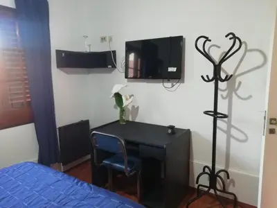 a bedroom with a desk and a tv on the wall at La casa de Lily in Alta Gracia