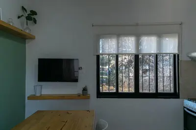 a living room with a tv and two windows at Departamentos Meraki in Villa Carlos Paz