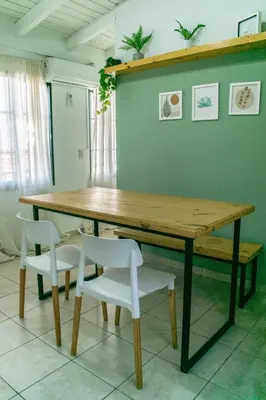 a wooden table with two white chairs and a table at Departamentos Meraki in Villa Carlos Paz