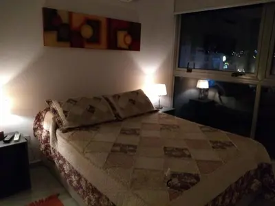 a bedroom with a bed and two lamps and a window at Departamentos NG CENTRO Carlos Paz in Villa Carlos Paz