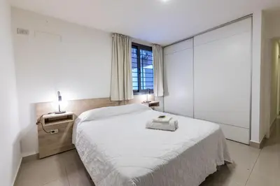 a white bedroom with a large bed and a window at Depto Familiar de dos habitaciones By Lofty in Cordoba