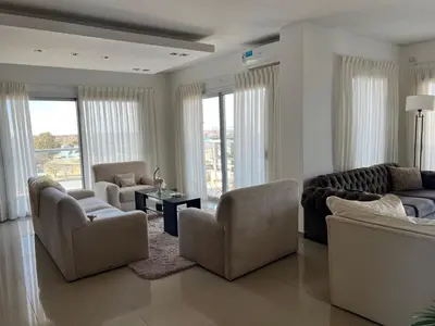 a living room with couches and chairs and windows at Departamento amplio y muy iluminado en 9 piso, con piscina in Río Cuarto