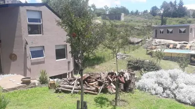 a house with a pile of logs next to a tree at El Refugio in Cordoba