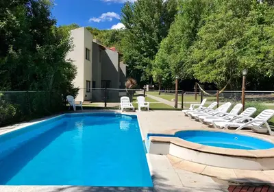 a swimming pool with lounge chairs next to a house at Cabañas El Francés in Merlo
