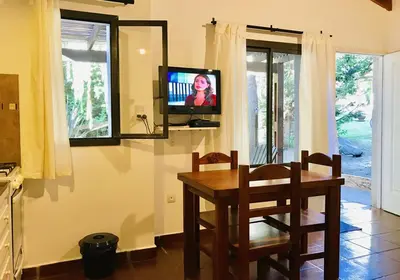 a dining room with a table and a tv on the wall at Cabañas El Francés in Merlo