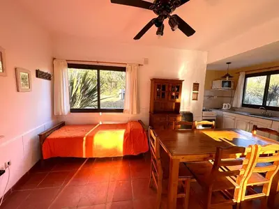 a bedroom with a bed and a table and a kitchen at Cabañas El Francés in Merlo
