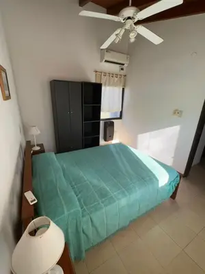 a bedroom with a green bed with a ceiling fan at Cabañas El Francés in Merlo
