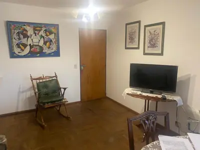 a living room with a television and a chair at Depto Boulevard Illia in Cordoba