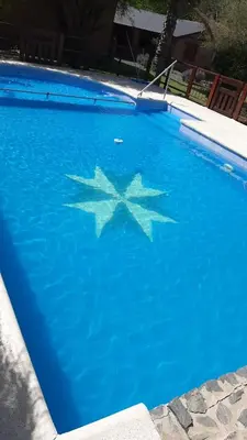a large blue swimming pool with a star in the water at Cabañas Ranger in Santa Rosa de Calamuchita
