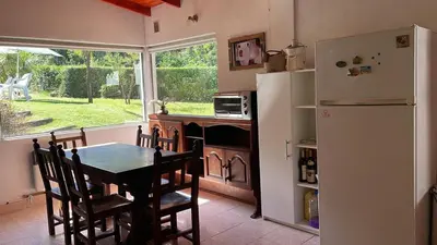 a kitchen with a table and a refrigerator at Casa con jardín, pileta, asador, y vistas al lago en Embalsina in Villa del Dique
