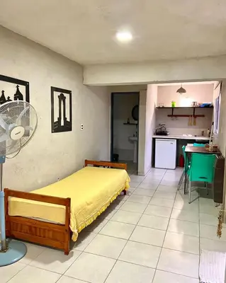 a bedroom with a yellow bed and a kitchen at Calamuchita Alquileres in Santa Rosa de Calamuchita