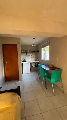 a kitchen with a table and green chairs in a room at Calamuchita Alquileres in Santa Rosa de Calamuchita