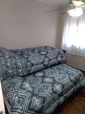 a bed with a blue and white bedspread and a window at Depto Plaza España in Cordoba