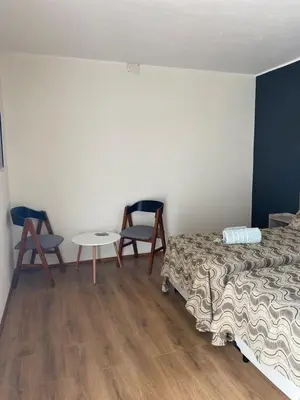 a bedroom with a bed and two chairs and a table at Cañas Suites Villa Cura Brochero in Villa Cura Brochero