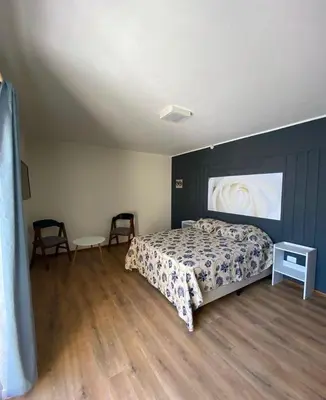 a bedroom with a bed and two chairs in it at Cañas Suites Villa Cura Brochero in Villa Cura Brochero