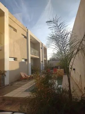 a building with a palm tree in front of it at Cañas Suites Villa Cura Brochero in Villa Cura Brochero